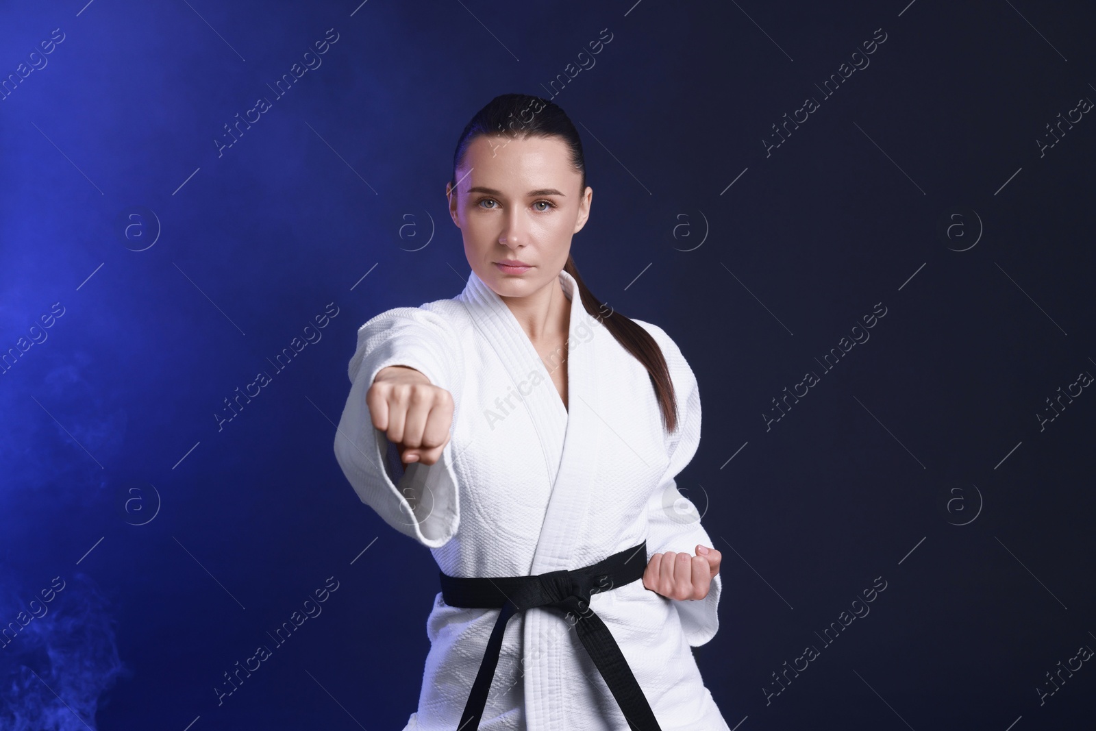 Photo of Karate fighter in kimono on dark blue background