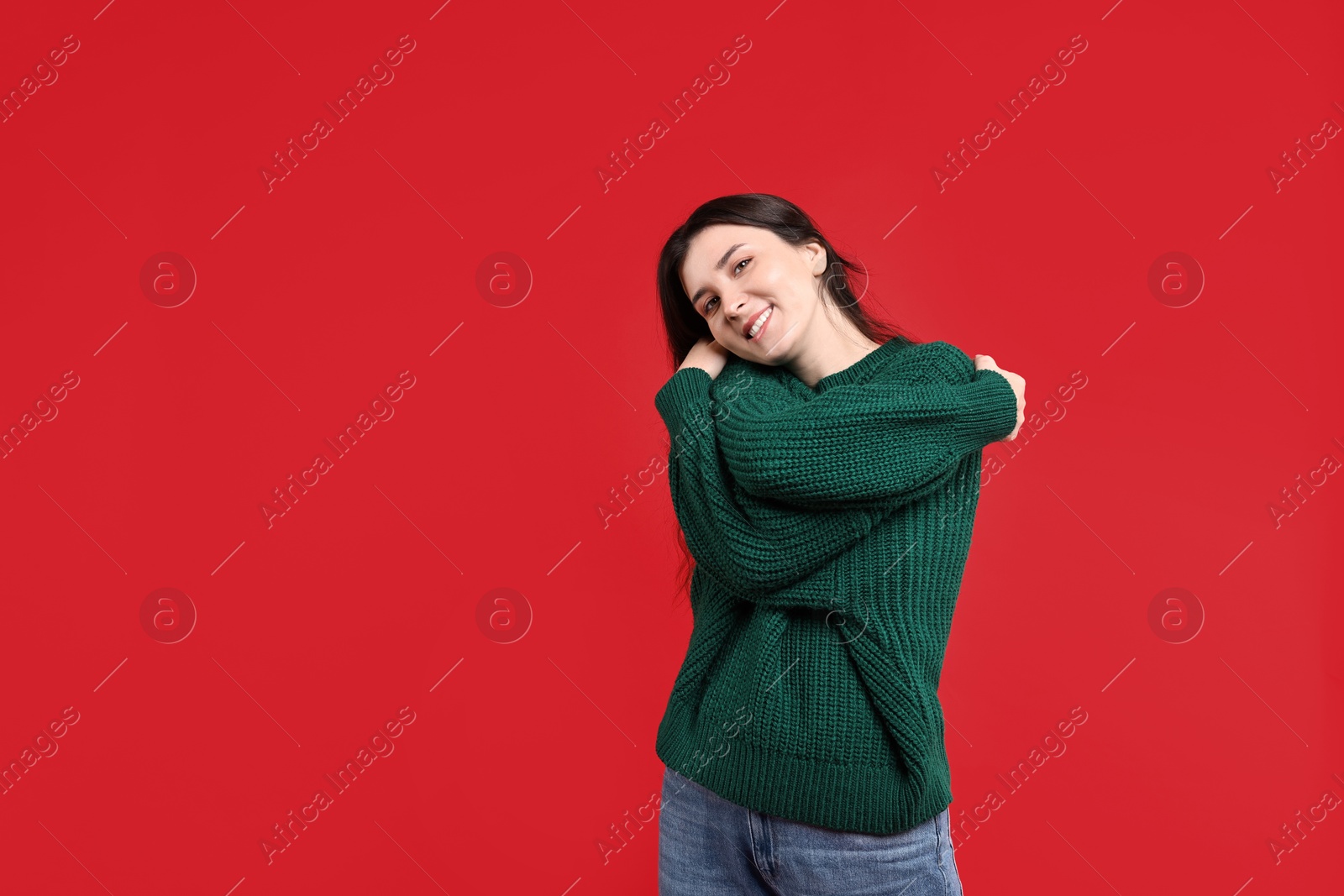 Photo of Beautiful young woman hugging herself on red background, space for text