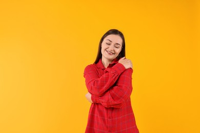 Photo of Beautiful young woman hugging herself on yellow background