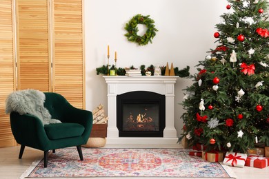 Photo of Decorated Christmas tree near fireplace in room. Festive interior design