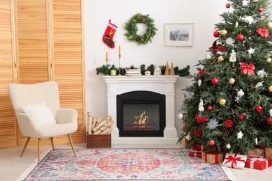 Photo of Decorated Christmas tree near fireplace in room. Festive interior design