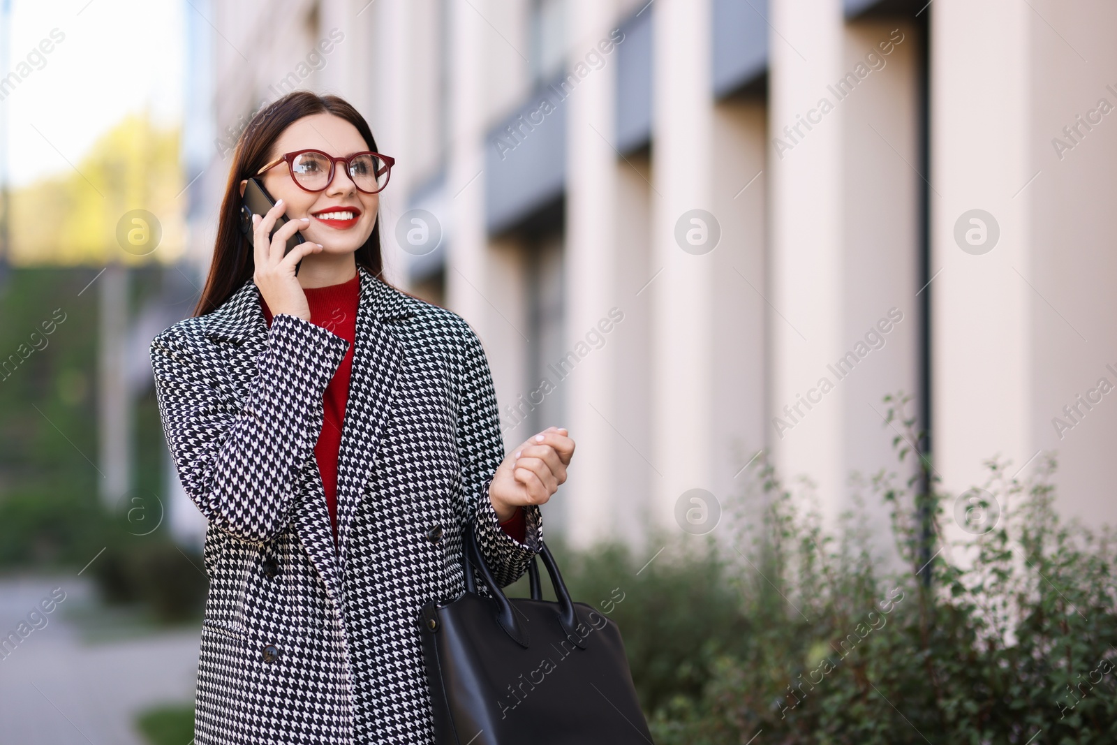 Photo of Beautiful woman in stylish suit talking on smartphone outdoors. Space for text