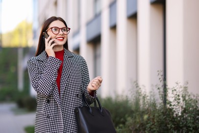 Photo of Beautiful woman in stylish suit talking on smartphone outdoors. Space for text