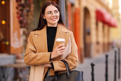 Photo of Smiling businesswoman in stylish outfit with paper cup outdoors. Space for text