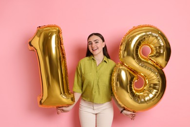 Photo of Coming of age party - 18th birthday. Happy young woman with number shaped balloons on pink background