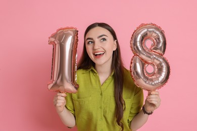 Photo of Coming of age party - 18th birthday. Happy young woman with number shaped balloons on pink background