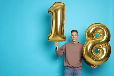 Photo of Coming of age party - 18th birthday. Happy young man with number shaped balloons on light blue background, space for text