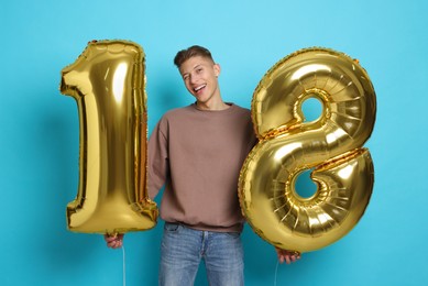 Coming of age party - 18th birthday. Happy young man with number shaped balloons on light blue background