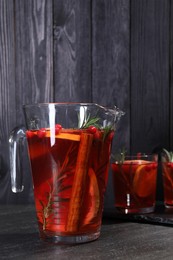 Photo of Delicious punch in jug and glasses on black table