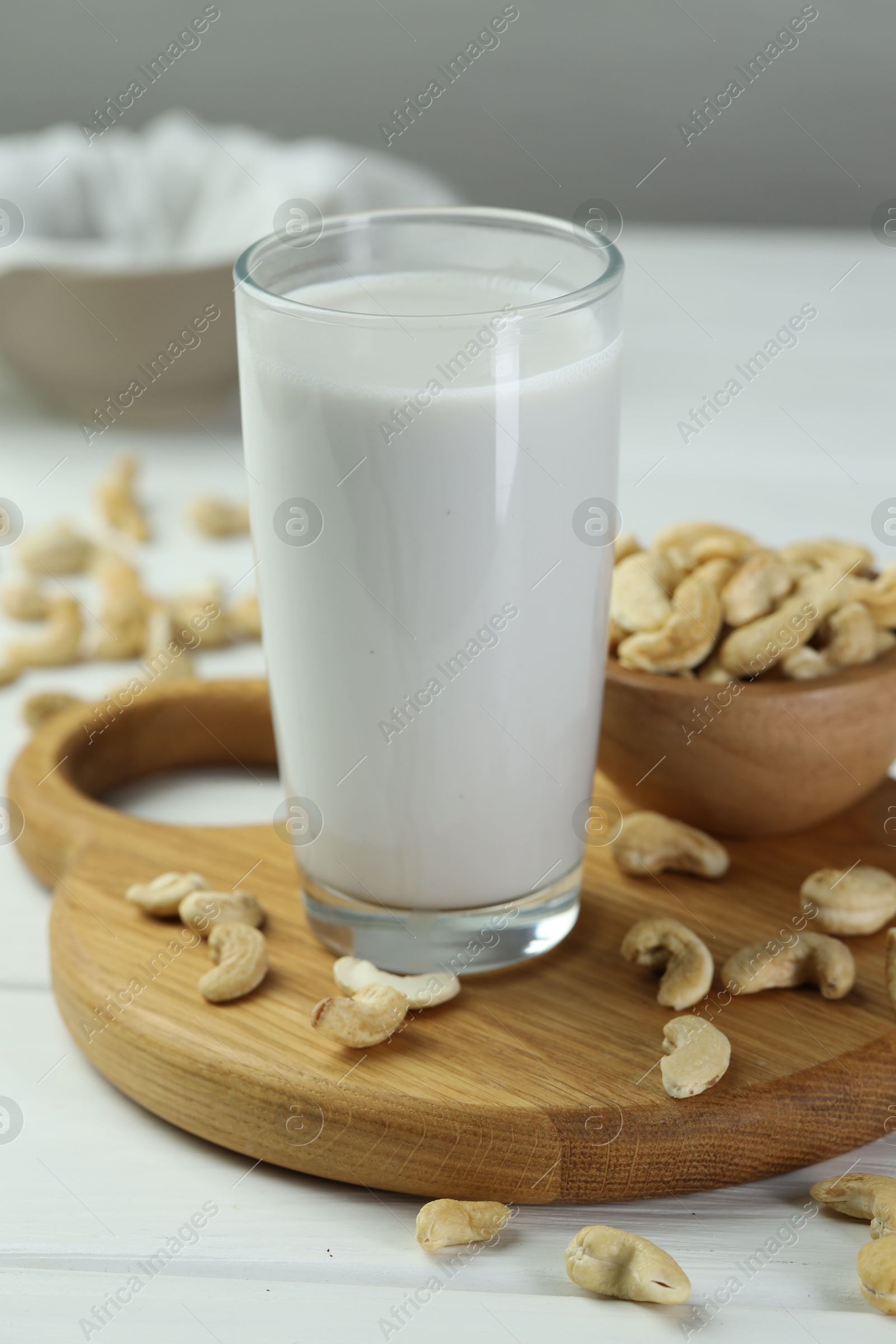 Photo of Fresh cashew milk in glass and nuts on white wooden table, closeup