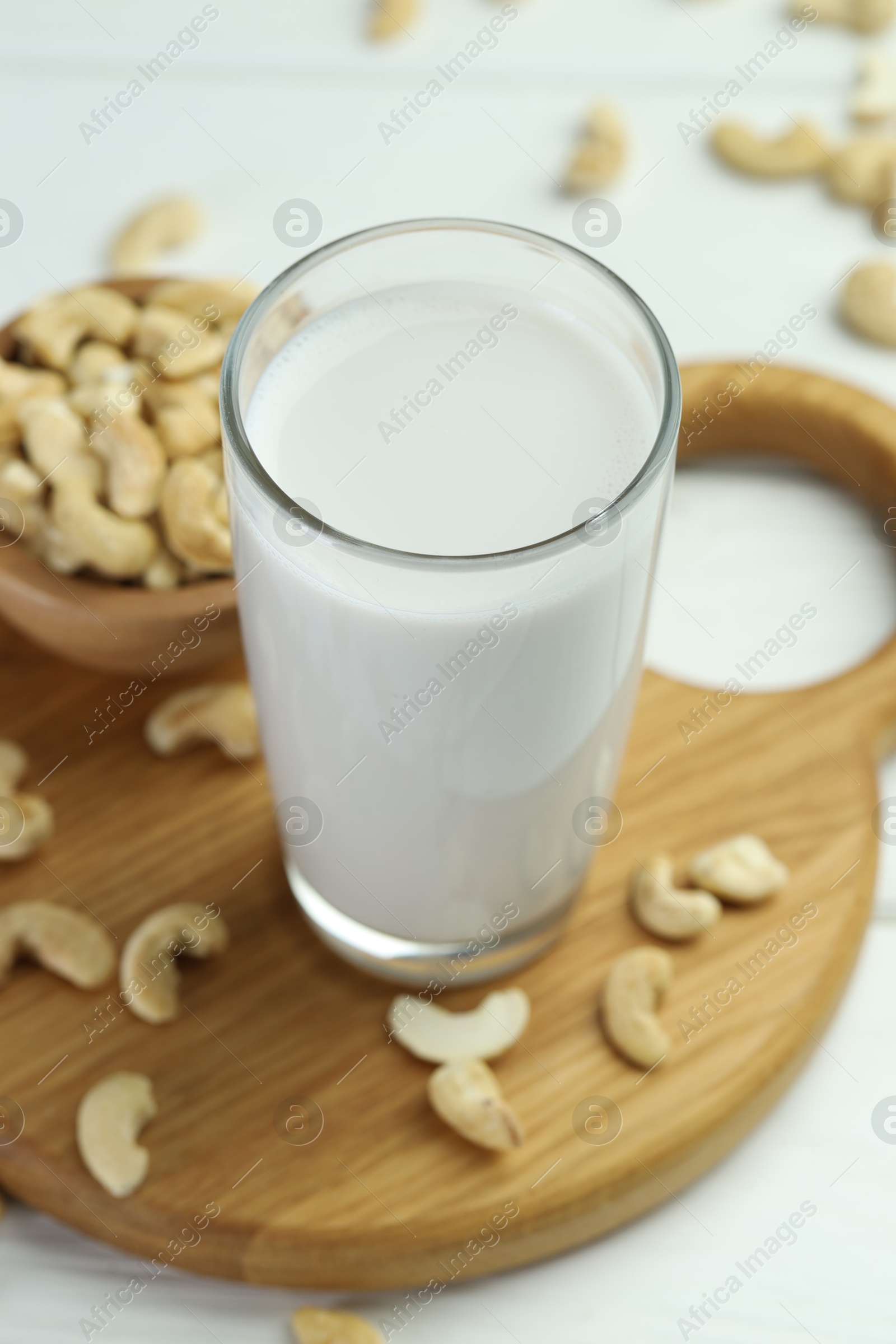 Photo of Fresh cashew milk in glass and nuts on white table, closeup