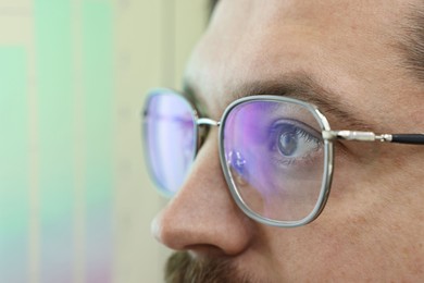 Photo of Man wearing stylish glasses on blurred background, closeup