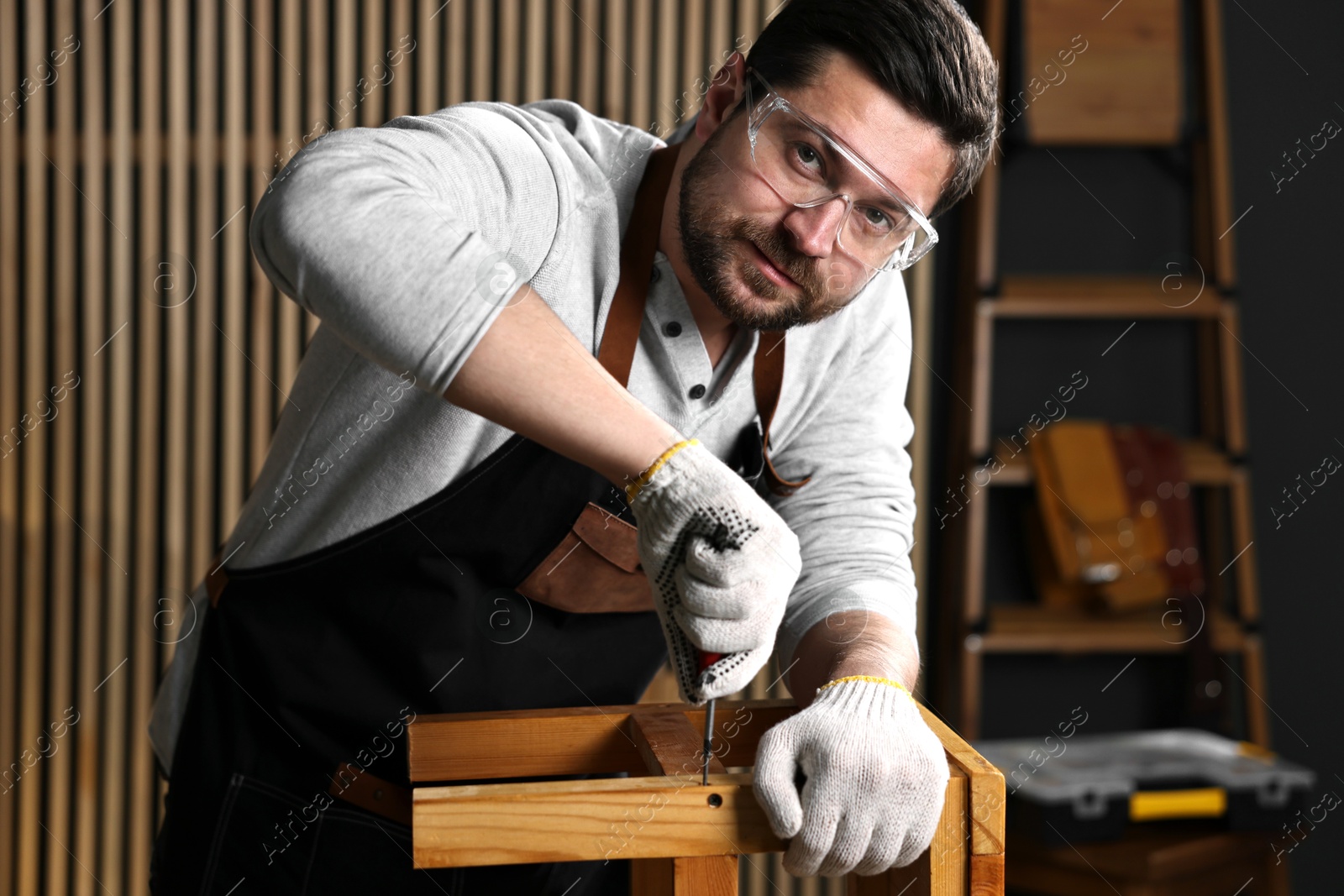 Photo of Professional carpenter repairing wooden stool in workshop