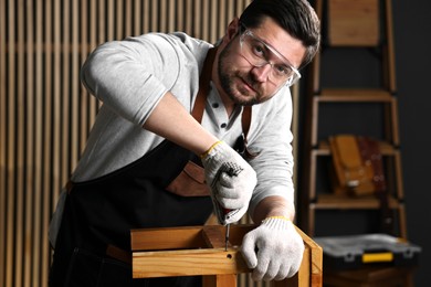 Photo of Professional carpenter repairing wooden stool in workshop