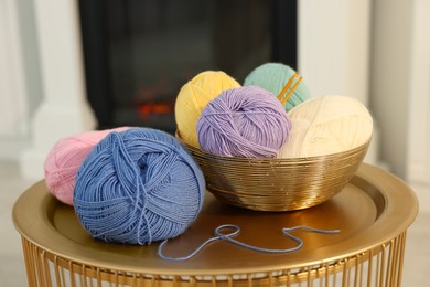 Photo of Colorful yarns and crochet hooks on coffee table indoors