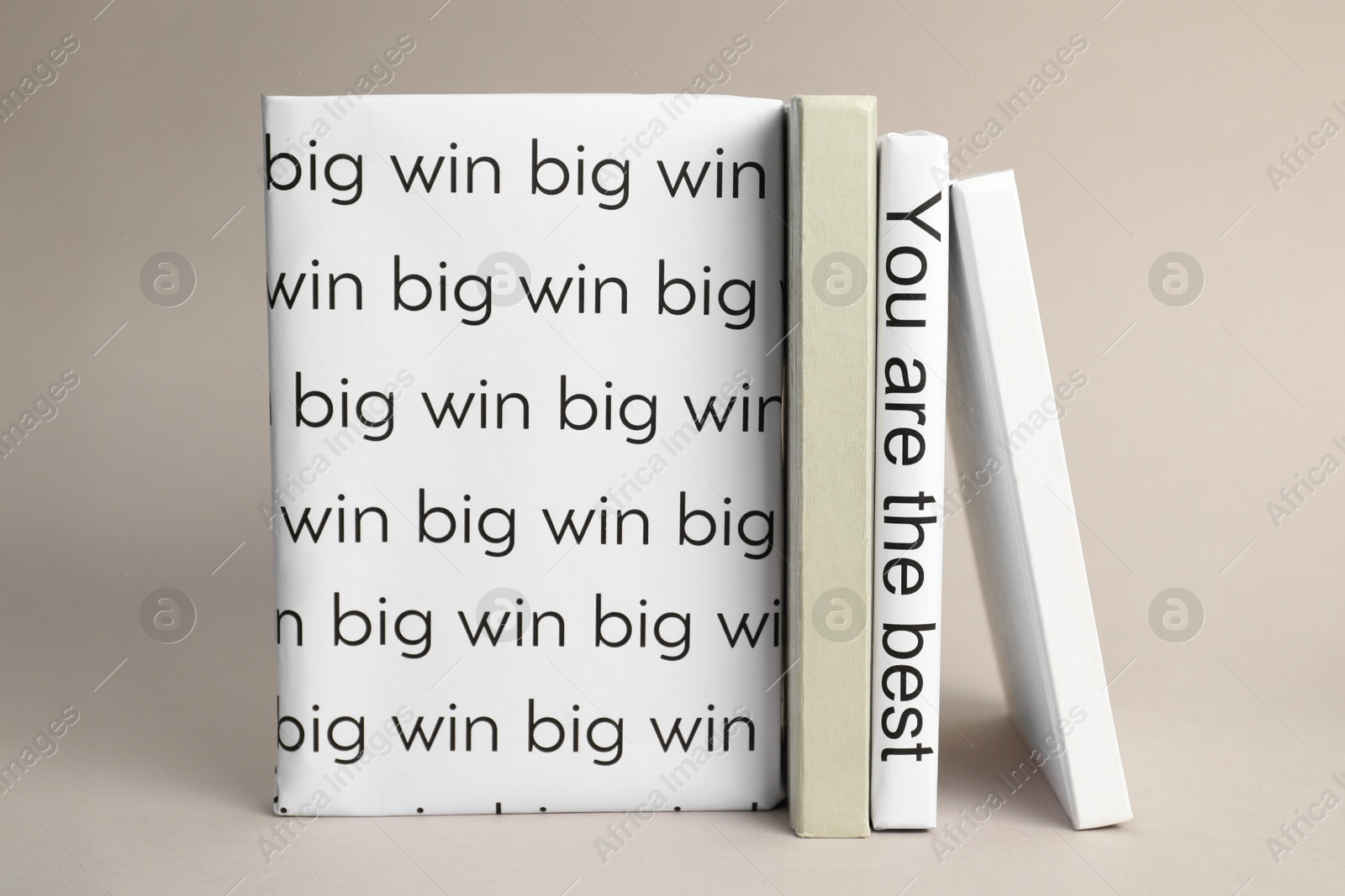 Photo of White books with phrases You are the best and Big win between ones on light grey background