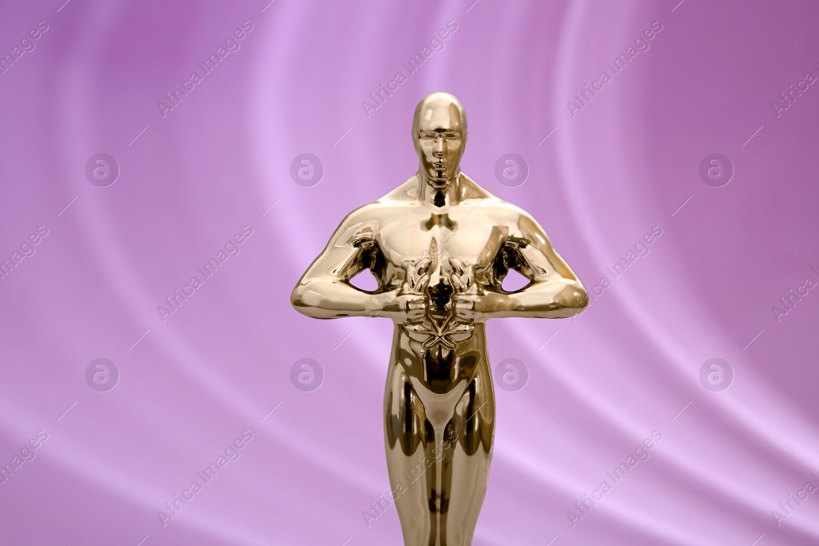 Photo of Golden trophy in shape of human figure on violet background