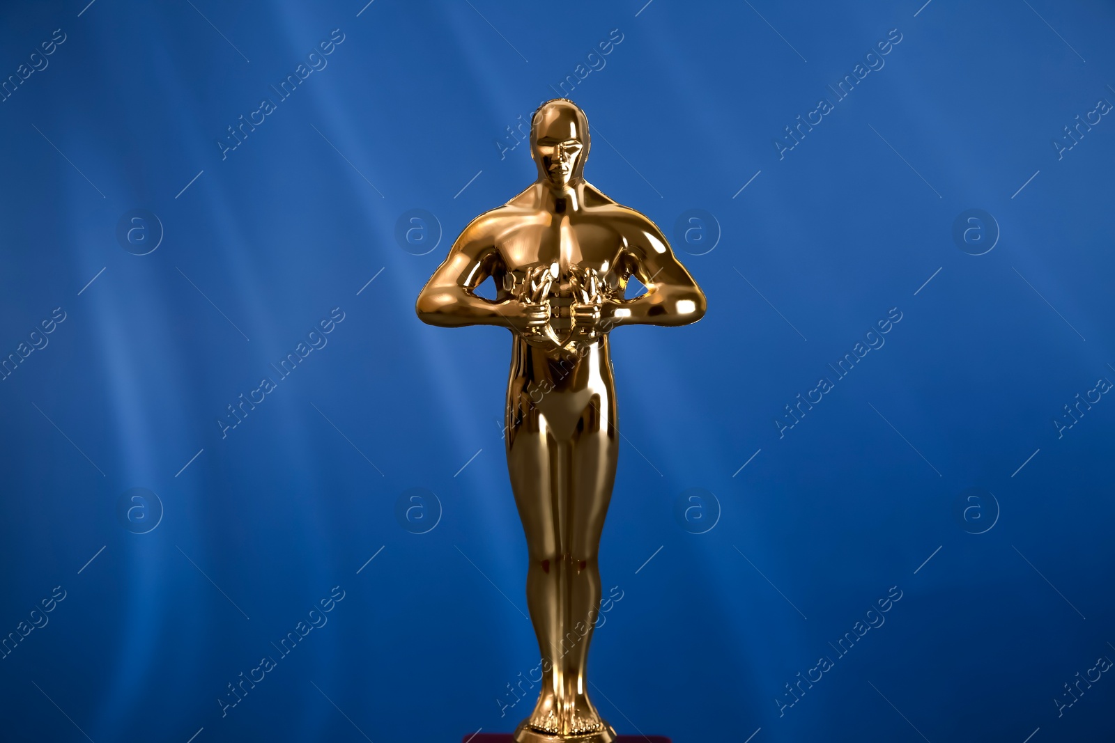 Photo of Golden trophy in shape of human figure on blue background