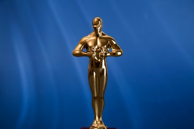 Photo of Golden trophy in shape of human figure on blue background