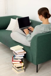 Student in headphones studying with laptop on sofa at home