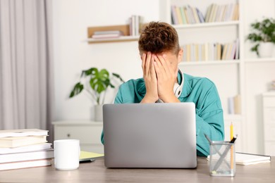 Photo of Student with headphones studying at table indoors