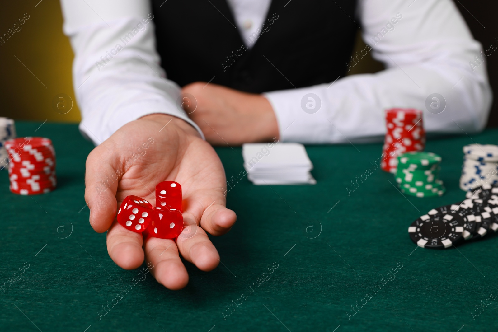 Photo of Professional croupier with dice at gambling table, closeup