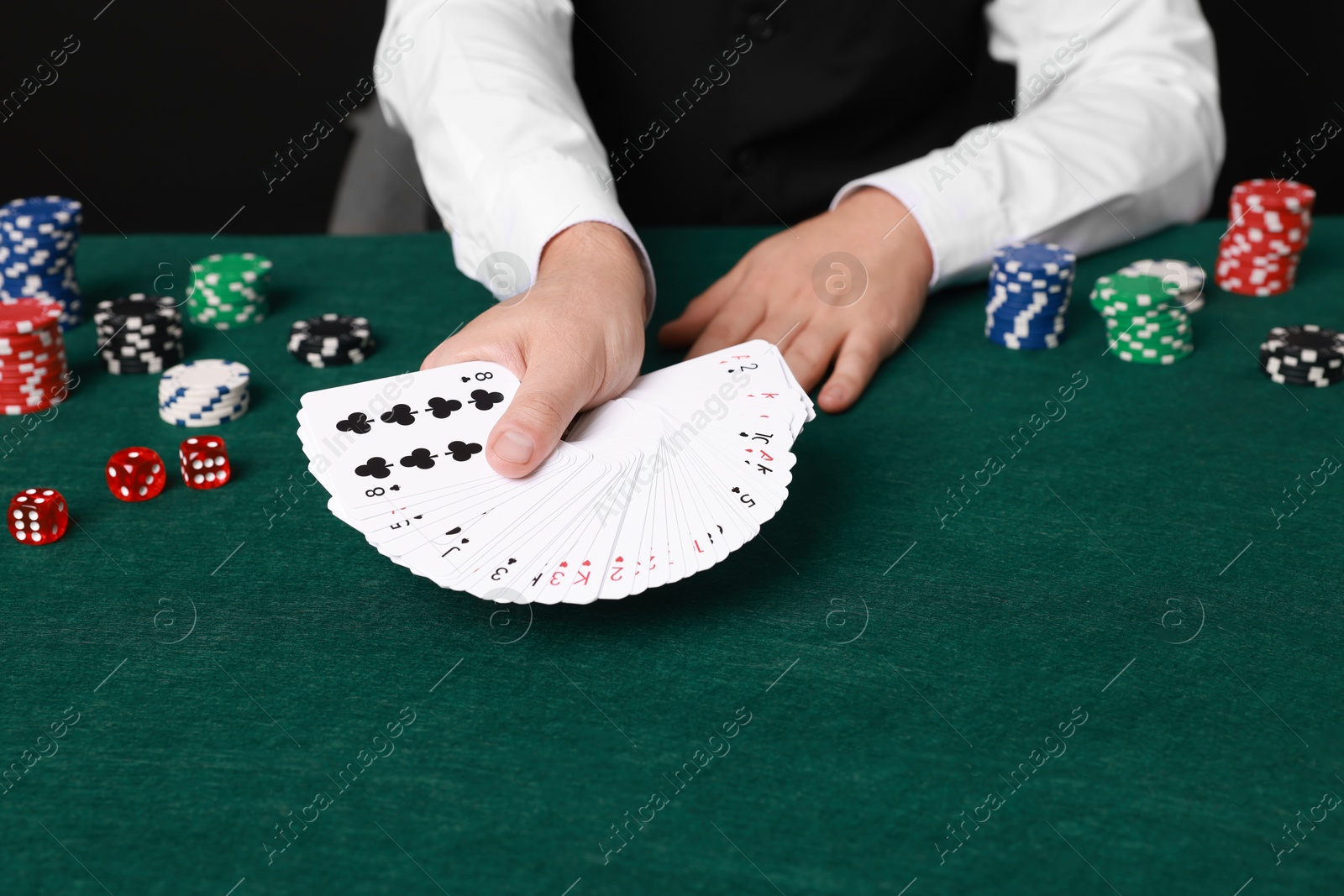 Photo of Professional croupier with playing cards at gambling table, closeup