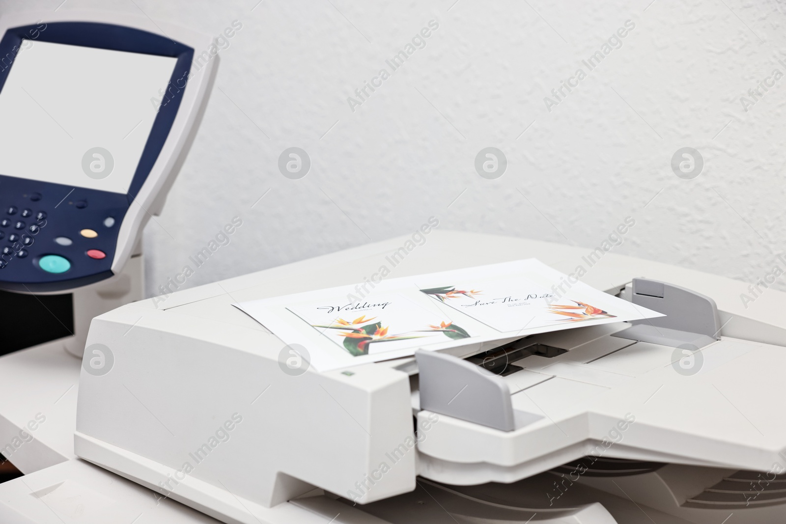 Photo of Modern printer with printed wedding invitation cards indoors, closeup. Printing house