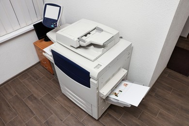 Photo of Modern printer with paper indoors. Printing house