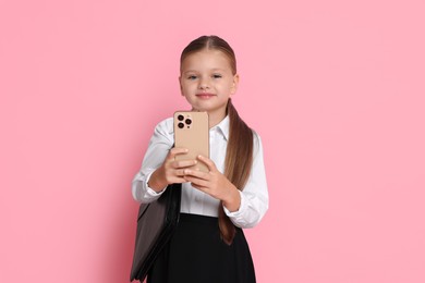 Photo of Little girl with briefcase and smartphone pretending to be businesswoman on pink background. Dreaming of future profession