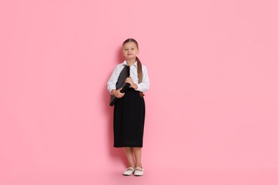 Little girl with briefcase pretending to be businesswoman on pink background. Dreaming of future profession