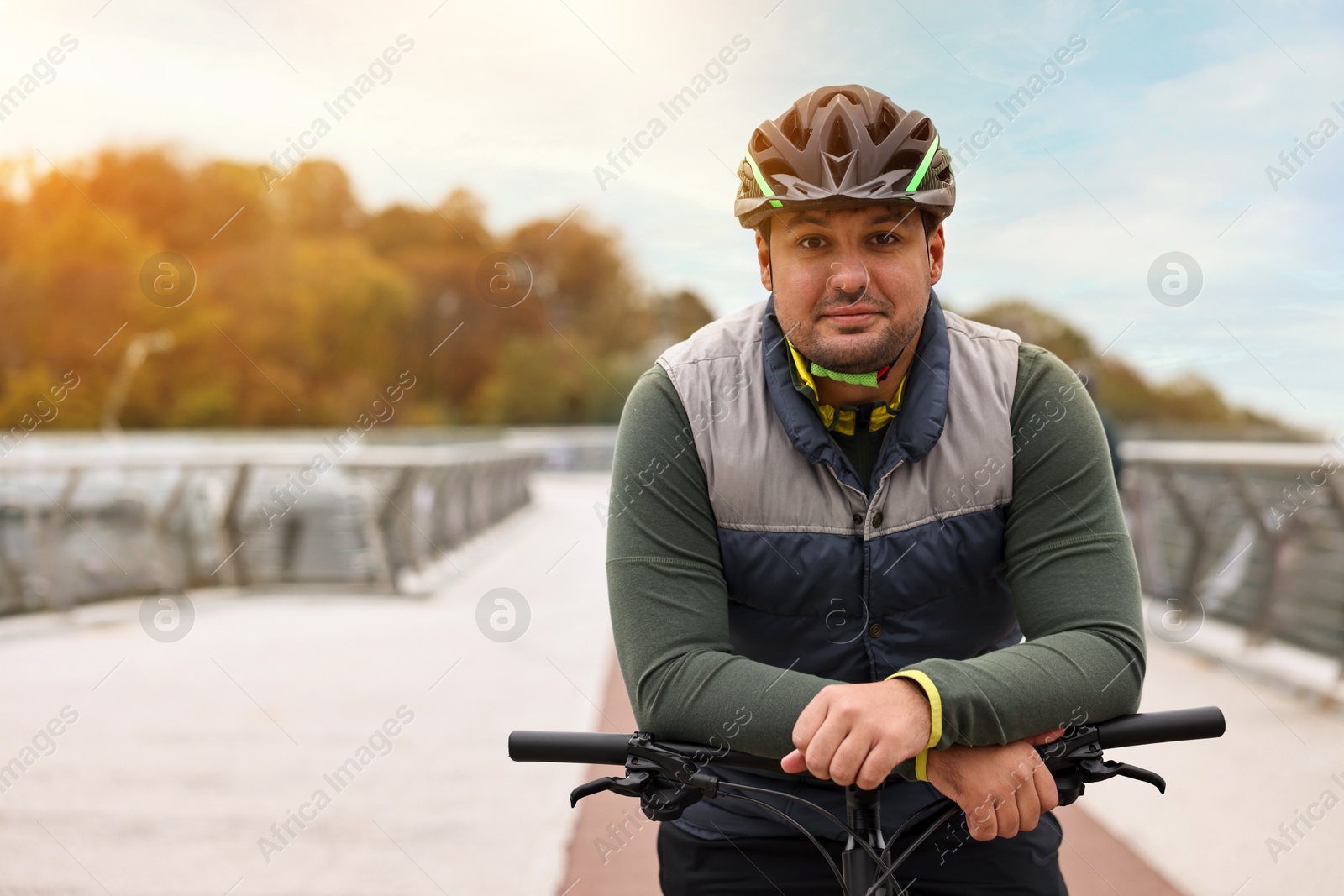 Photo of Man with helmet and bicycle outdoors, space for text