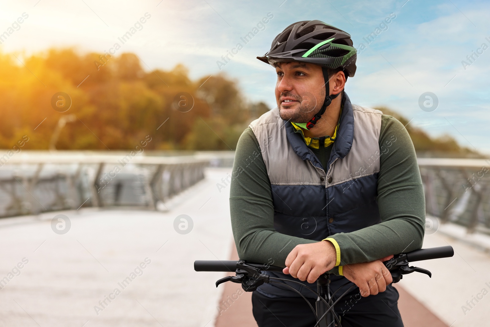 Photo of Man with helmet and bicycle outdoors, space for text