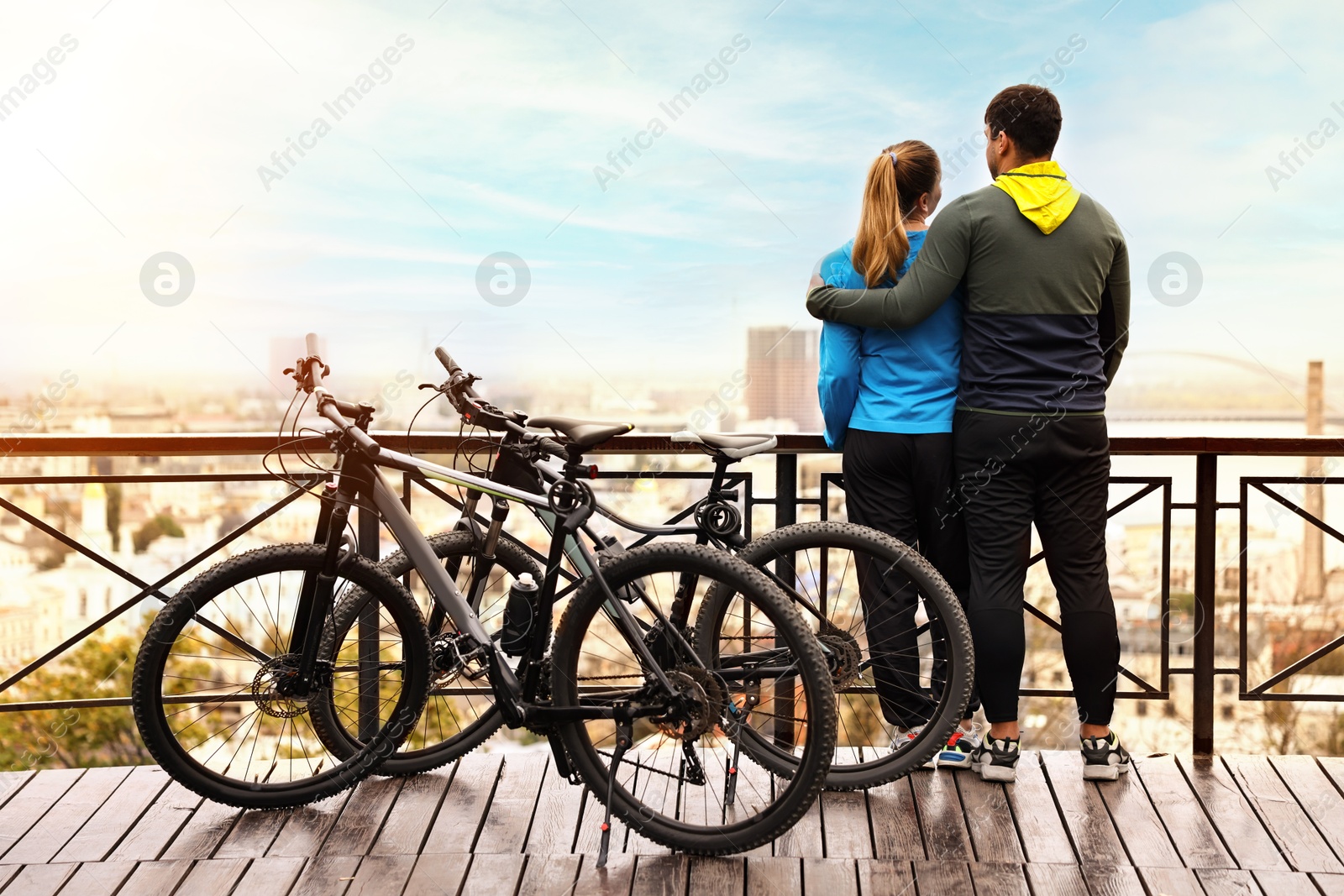 Photo of Beautiful happy couple with bicycles spending time together outdoors, back view