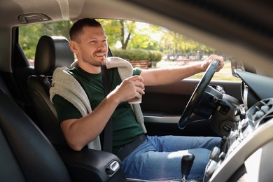 Photo of Man with cup of coffee driving modern car