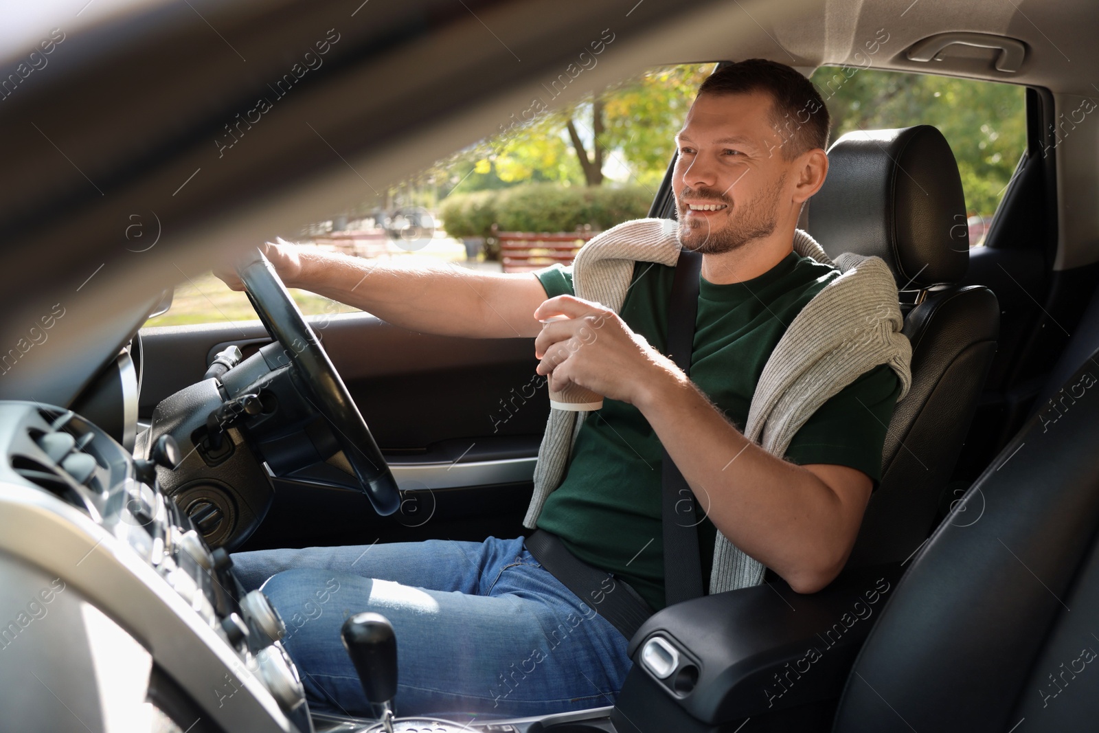 Photo of Man with cup of coffee driving modern car