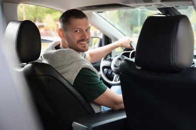 Photo of Happy man behind steering wheel of modern car