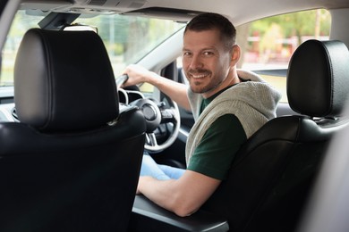 Photo of Happy man behind steering wheel of modern car