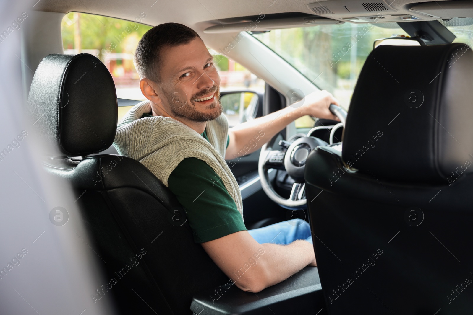 Photo of Happy man behind steering wheel of modern car