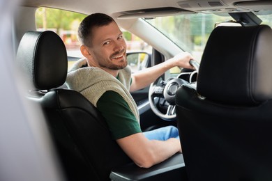 Happy man behind steering wheel of modern car