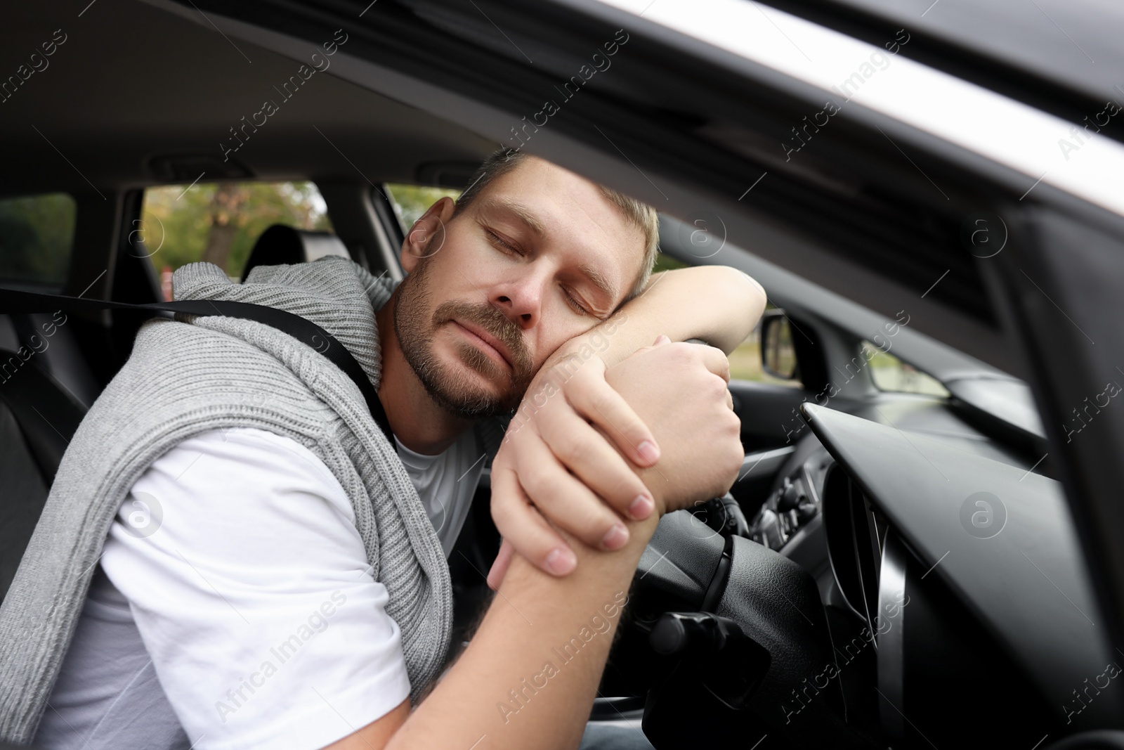 Photo of Tired man sleeping on steering wheel in car