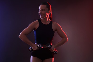 Photo of Woman exercising with dumbbells in smoke on dark background