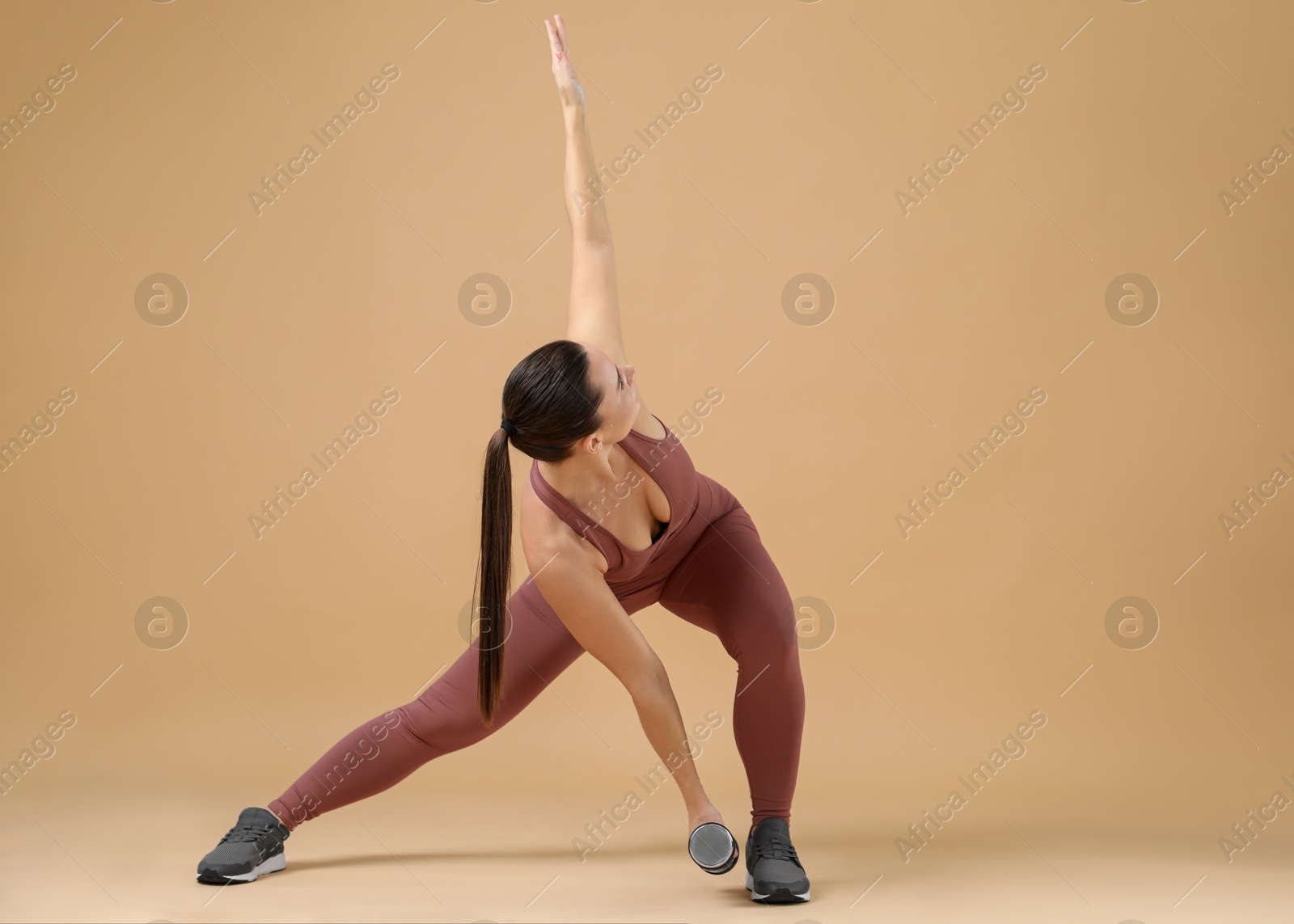 Photo of Woman exercising with dumbbell on beige background, space for text