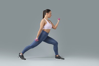 Photo of Woman exercising with dumbbells on light grey background, space for text