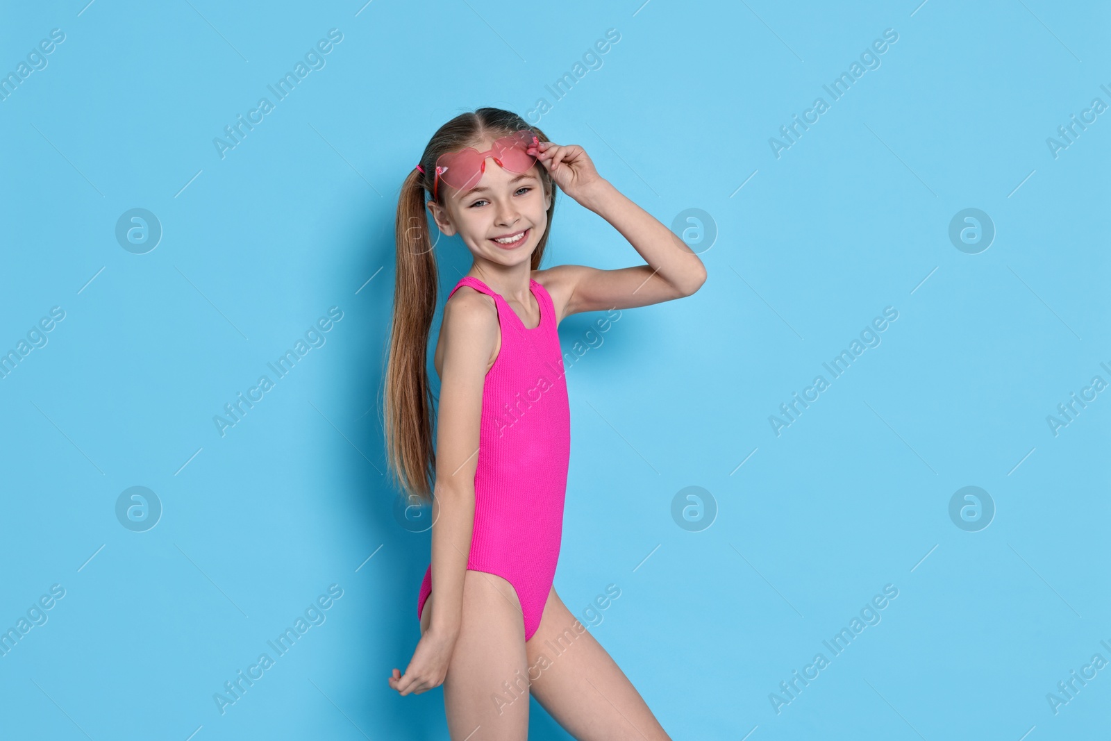 Photo of Happy girl in beachwear on light blue background