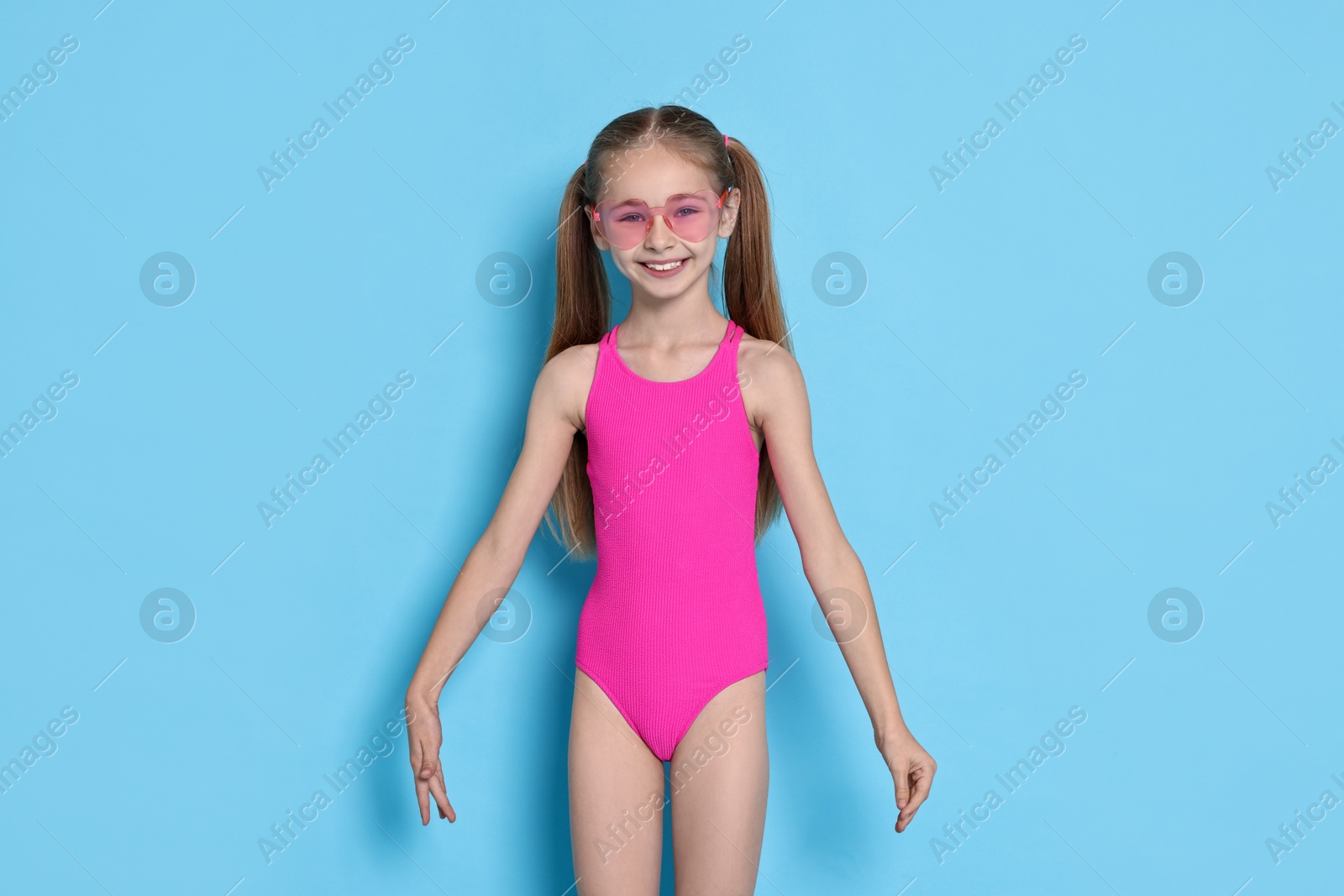 Photo of Happy girl in beachwear on light blue background