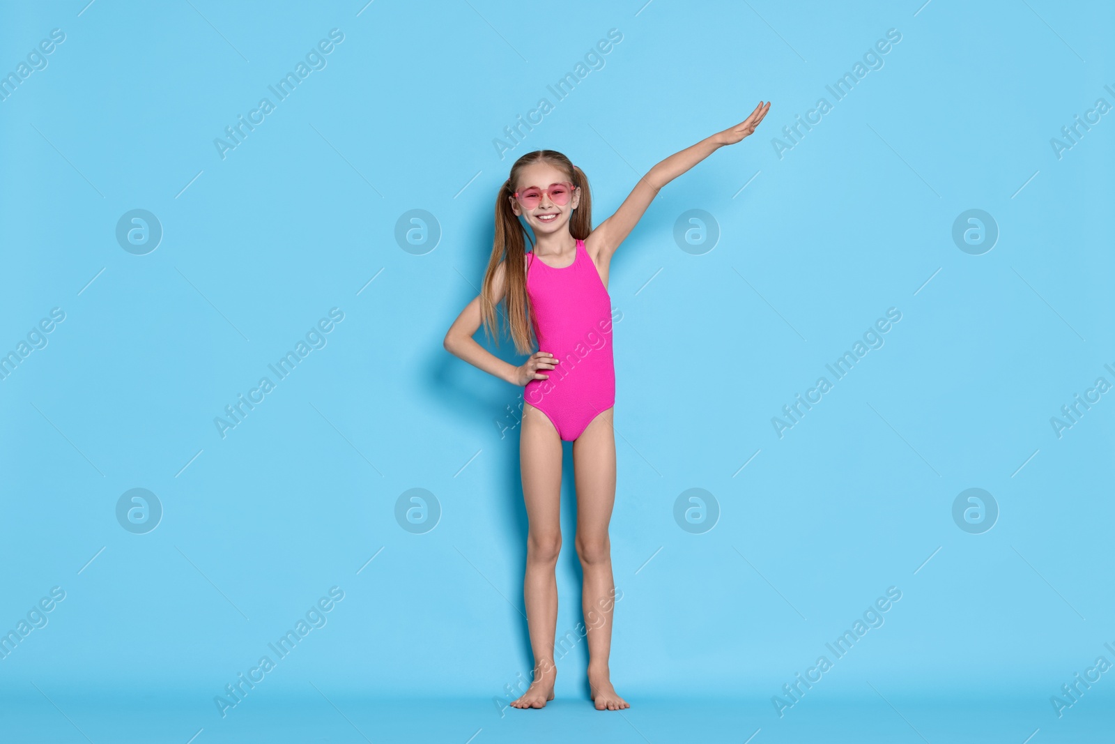 Photo of Happy girl in beachwear on light blue background