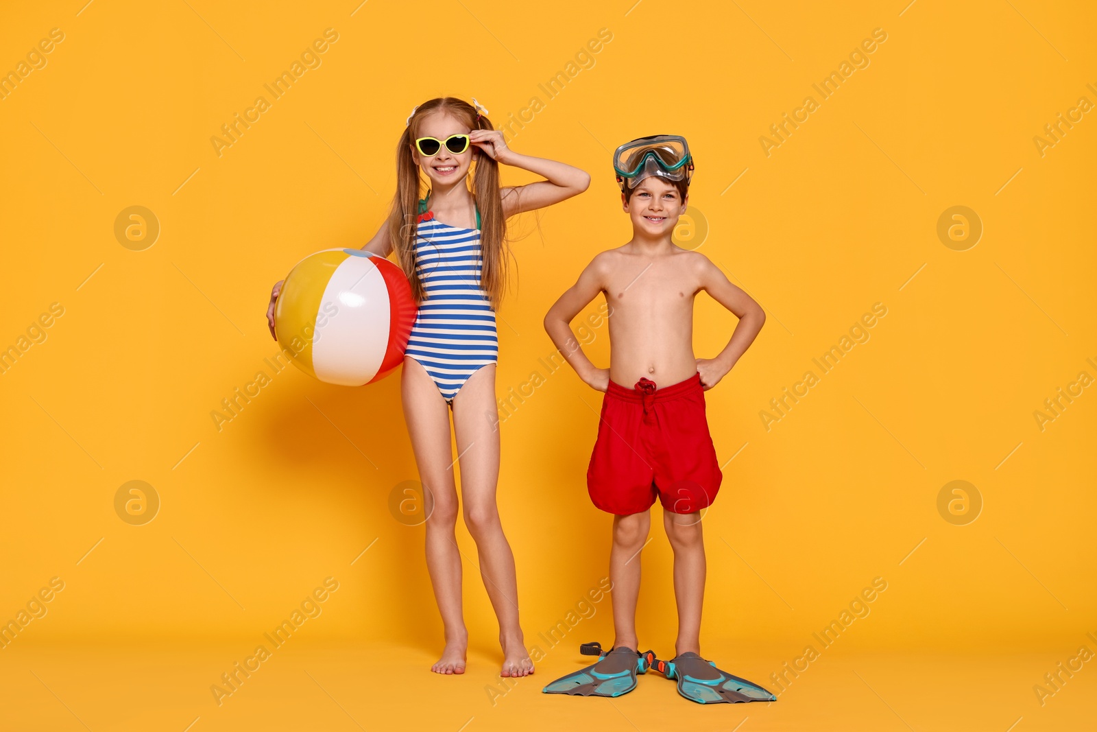 Photo of Happy little kids in beachwear on orange background