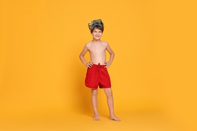 Photo of Little boy in beachwear with diving mask on orange background