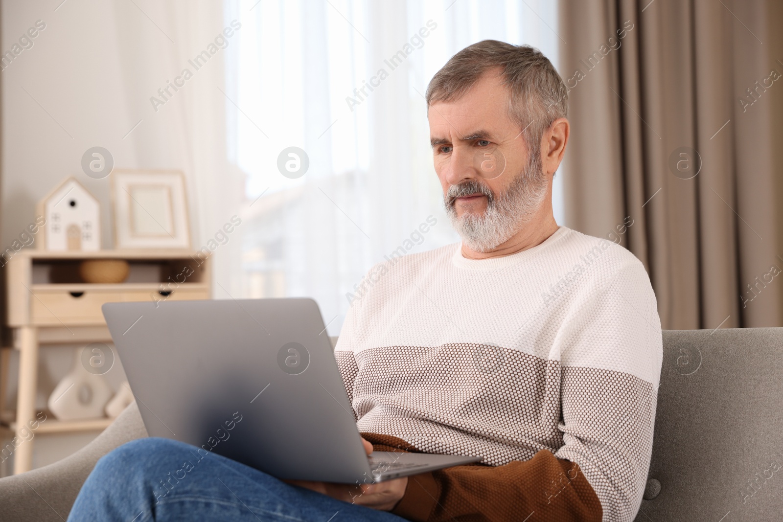 Photo of Mature man with laptop on sofa at home